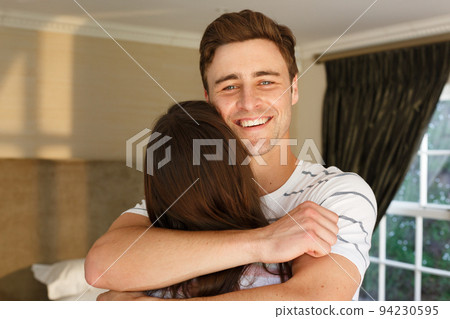Caucasian couple embracing man smiling woman with back to camera Caucasian couple embracing man smiling woman with back to camera 94230595