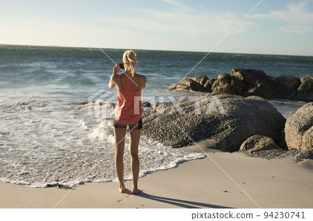 Woman using phone on the beach 94230741
