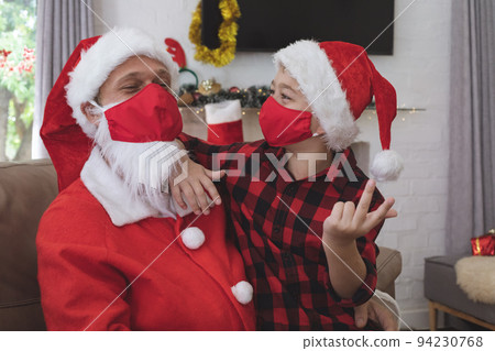 Santa Claus and boy wearing face mask at home 94230768