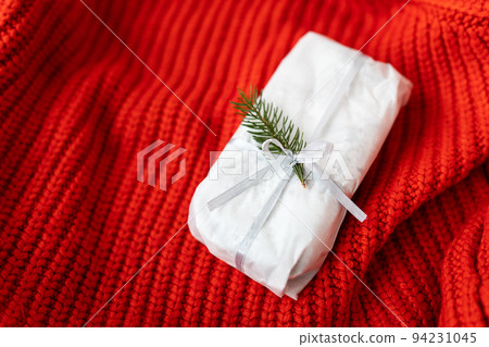 Christmas German pastry with a beautiful ribbon and a Nobilis branch on a red background. Traditional Christmas dessert. Stollen at Christmas. 94231045