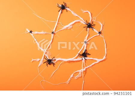 Multiple spider toys forming a spider web with copy space against orange background Multiple spider toys forming a spider web with copy space against orange background 94231101