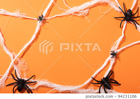 Multiple spider toys forming a spider web with copy space against orange background Multiple spider toys forming a spider web with copy space against orange background 94231106