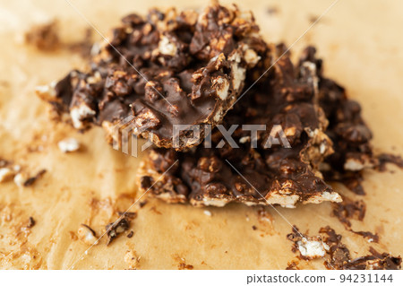 Close-up texture of peanut butter, puffed rice and chocolate, very tasty DIY dessert, dessert slices on parchment. Close-up texture of peanut butter, puffed rice and chocolate, very tasty DIY dessert, dessert slices on parchment. 94231144