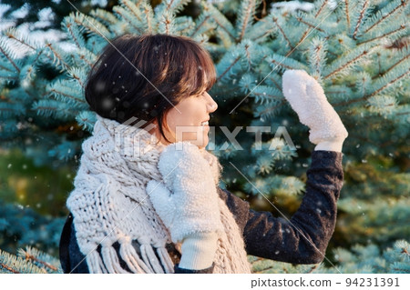 Young woman in scarf mittens looking away waving hand in winter snowy sunny weather 94231391