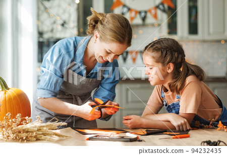 Happy smiling family mother and daughter making Halloween home decorations together 94232435