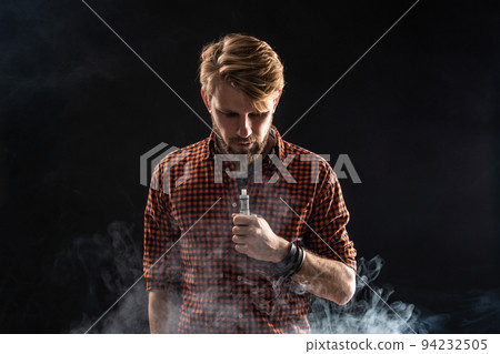 A young man with a beard and a stylish hairstyle in a shirt, smoking a cigarette, a viper, a room, a studio, smoke, enjoyment 94232505