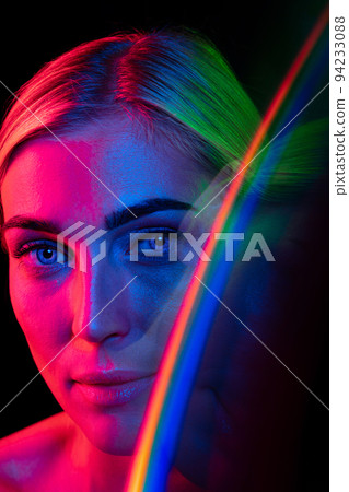 Young beautiful woman with well-kept skin and stylish makeup isolated over dark background in pink neon light. Concept of beauty, art, fashion 94233088