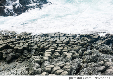 natural cobblestone causeway, formed by the ends of lava columns, descends into the sea surf natural cobblestone causeway, formed by the ends of lava columns, descends into the sea surf 94233464