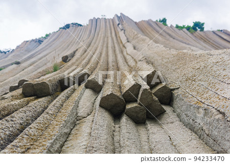 basalt columns forming a coastal rock at Cape Stolbchaty on Kunashir Island, close-up basalt columns forming a coastal rock at Cape Stolbchaty on Kunashir Island, close-up 94233470