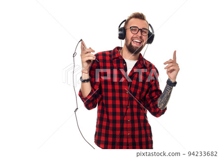 Young hipster man in checkered shirt and glasses wearing earphones looking happy on white background. 94233682