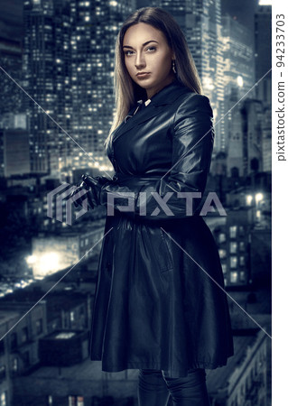 Retro portrait of inaccessible beautiful woman in black cloak stands against the background of the night city. Film noir. Vintage Hollywood style. Studio shot. 94233703