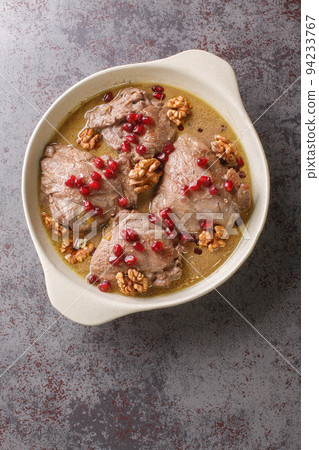 Fesenjan is an Iranian pomegranate and chicken stew made with ground walnuts, onions, squash, cinnamon, and pomegranate molasses close-up on the table. Vertical top view 94233767