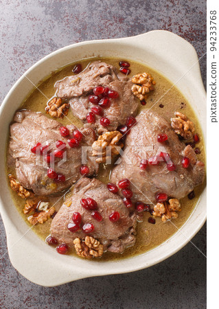 Fesenjan Persian pomegranate walnuts and Chicken Stew close-up in a plate. Vertical top view 94233768