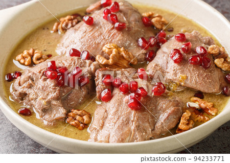 Khoreh Fesenjan tender chicken is cooked in a walnut pomegranate sauce close-up in a pan. Horizontal 94233771