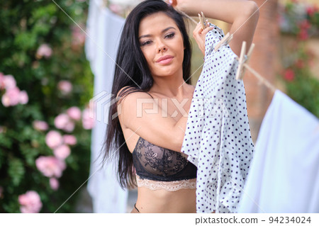 italian woman hangs up the laundry in garden 94234024