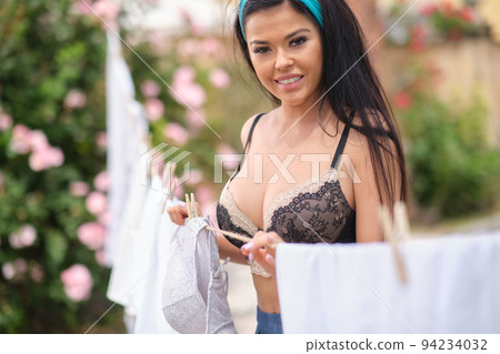 italian woman hangs up the laundry in garden 94234032