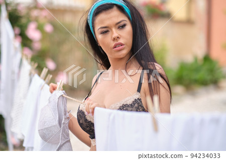 italian woman hangs up the laundry in garden 94234033