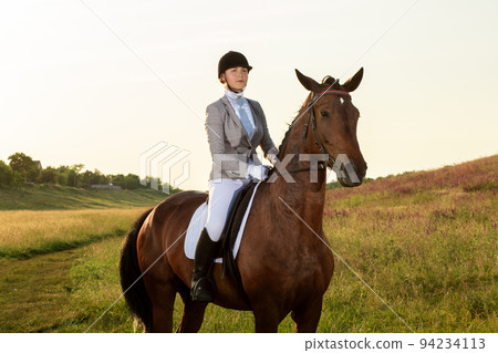 Equestrian sport. Young woman riding horse on dressage advanced test 94234113
