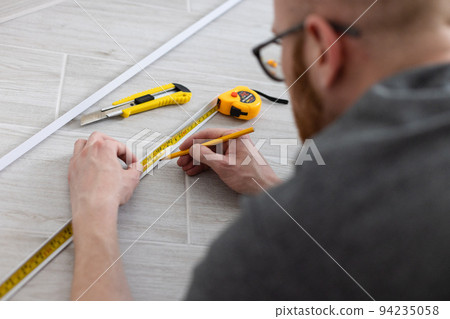 Man measuring decorative plastic corner. Man with measuring tools. Man measuring decorative plastic corner. Man with measuring tools. 94235058