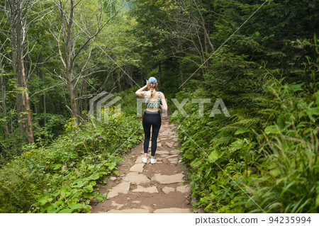 Traveler woman with backpack walking on beautiful green forest. Poland 94235994