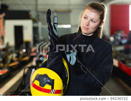 Young woman puts equipment for karting Young woman puts equipment for karting 94236532