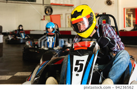 Man and his friends competing on racing cars 94236562