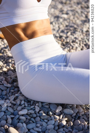Cropped image of strong fit female body with well- defined abs in white sports wear Cropped image of strong fit female body with well- defined abs in white sports wear 94236820