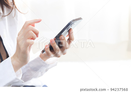 Woman operating a smartphone 94237568