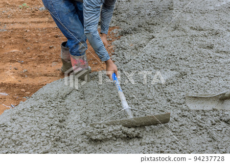 Pouring concrete for a car parking driveway is the work of a worker 94237728