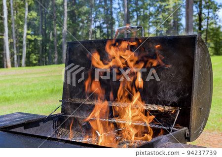 An example of how to prepare a BBQ for grilling meat using firewood and a blazing fire source 94237739