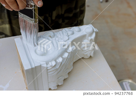 Painting wooden corbels for a kitchen island with worker using paintbrush 94237768