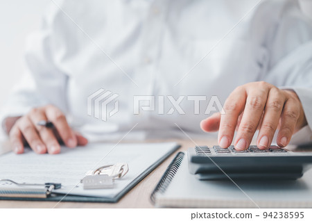 woman calculates her budget before signing a real estate project contract with a house model. woman calculates her budget before signing a real estate project contract with a house model. 94238595