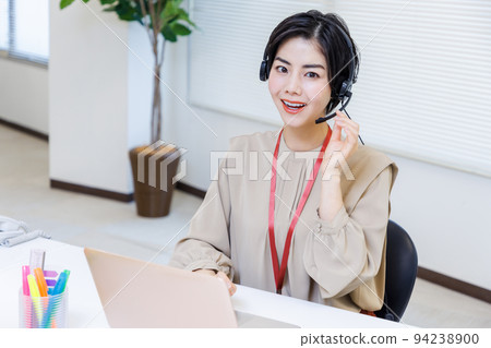 在辦公室工作時戴耳機的年輕女性 94238900