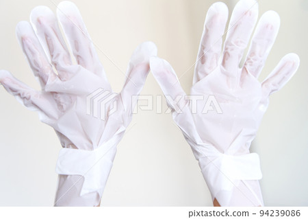After a shower, a girl wrapped in a towel uses cosmetic gloves to moisturize the skin of her hands. Cosmetic trends for body care at home After a shower, a girl wrapped in a towel uses cosmetic gloves to moisturize the skin of her hands. Cosmetic trends for body care at home 94239086