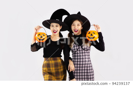 Halloween theme, young asian woman in black costume witch hat holding and carrying orange pumpkin bucket and lantern posing happy smiling on white background. Halloween theme, young asian woman in black costume witch hat holding and carrying orange pumpkin bucket and lantern posing happy smiling on white background. 94239137
