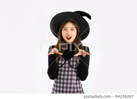 Young asian woman in black halloween costume wearing witch's hat posing on white background. 94239267