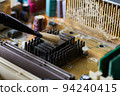 Brush cleaning an old computer board from dust and dirt. Close-up. 94240415