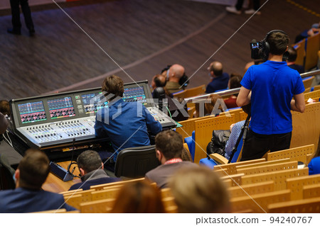 Men operating sound recording equipment and video camera in conference hall Men operating sound recording equipment and video camera in conference hall 94240767