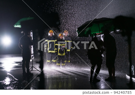 Behind the scene of Firefighters photo and cinema set with rain use a water hose to eliminate a fire hazard. Behind the scene of Firefighters photo and cinema set with rain use a water hose to eliminate a fire hazard. 94240785