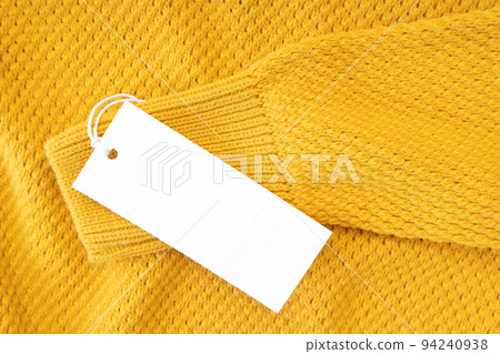 White blank rectangular clothing tag on yellow knitted sweater isolated on white background White blank rectangular clothing tag on yellow knitted sweater isolated on white background 94240938