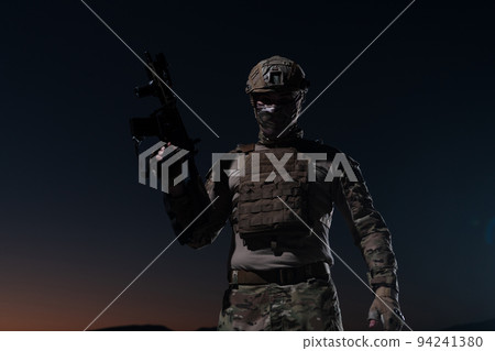 Army soldier in Combat Uniforms with an assault rifle, plate carrier and combat helmet going on a dangerous mission on a rainy night. Army soldier in Combat Uniforms with an assault rifle, plate carrier and combat helmet going on a dangerous mission on a rainy night. 94241380