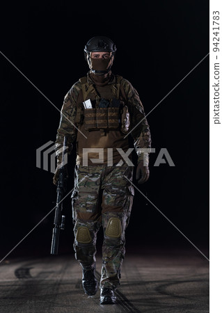 Army soldier in Combat Uniforms with an assault rifle, plate carrier and combat helmet going on a dangerous mission on a rainy night. Army soldier in Combat Uniforms with an assault rifle, plate carrier and combat helmet going on a dangerous mission on a rainy night. 94241783