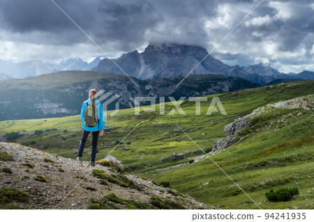 Girl with backpack on the hill looking at mountains at sunset 94241935