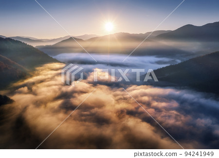 Mountains in low clouds at sunrise in summer. Aerial view Mountains in low clouds at sunrise in summer. Aerial view 94241949