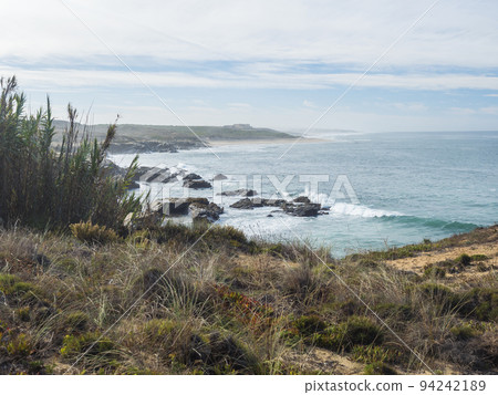 View of empty Praia da Ilha do Pessegueiro sand beach and fortress with ocean waves and sharp rocks and cllifs at wild Rota Vicentina coast near Porto Covo, Portugal. View of empty Praia da Ilha do Pessegueiro sand beach and fortress with ocean waves and sharp rocks and cllifs at wild Rota Vicentina coast near Porto Covo, Portugal. 94242189
