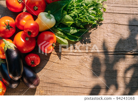 Organic food, harvest. Ripe vegetables red tomatoes sweet peppers eggplant greenery leaves lie table Organic food, harvest. Ripe vegetables red tomatoes sweet peppers eggplant greenery leaves lie table 94243168