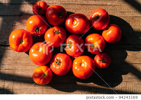 Organic food, harvest. Ripe red tomatoes lie on a wooden table. Top view flat lay Organic food, harvest. Ripe red tomatoes lie on a wooden table. Top view flat lay 94243169