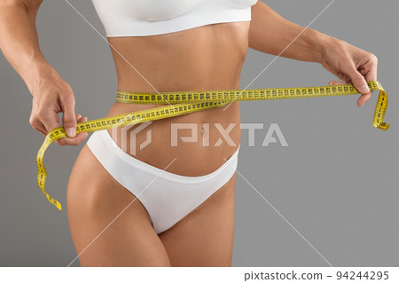 Closeup Shot Of Young Woman With Measuring Tape Checking Waist Size Closeup Shot Of Young Woman With Measuring Tape Checking Waist Size 94244295