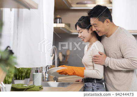 Loving korean husband supporting wife while she is washing dishes Loving korean husband supporting wife while she is washing dishes 94244473