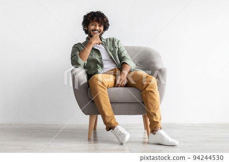 Relaxed indian guy chilling in arm chair over white background 94244530